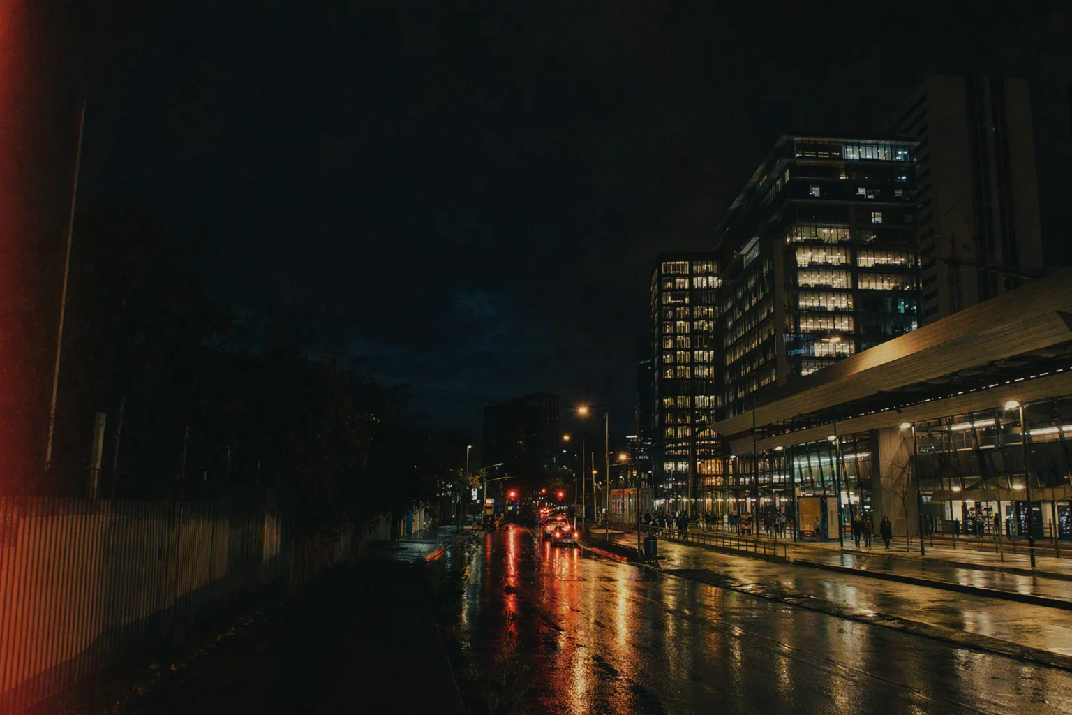 Propuesta visual de una calle urbana contemporánea durante la noche, con ventanas encendidas y pavimento mojado