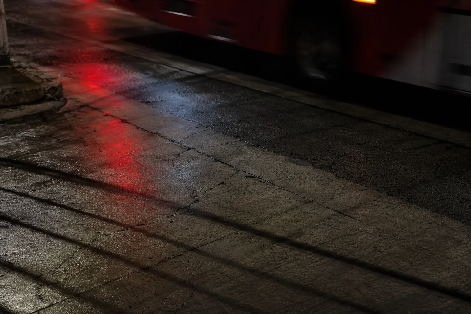 Reflejos rojos sobre pavimento urbano mojado durante la noche